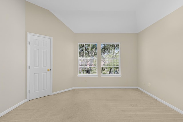empty room with light carpet, baseboards, and lofted ceiling