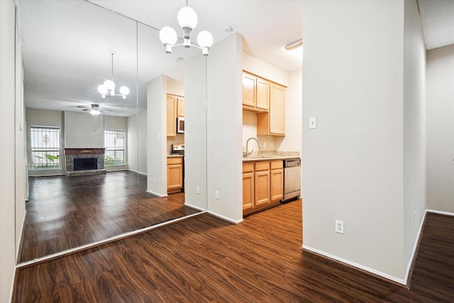 kitchen featuring a sink, white microwave, dark wood-style flooring, open floor plan, and stainless steel dishwasher