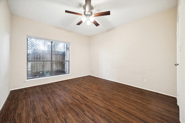 empty room with a textured ceiling, baseboards, dark wood-style flooring, and a ceiling fan