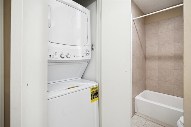washroom featuring stacked washing maching and dryer, laundry area, and light tile patterned flooring
