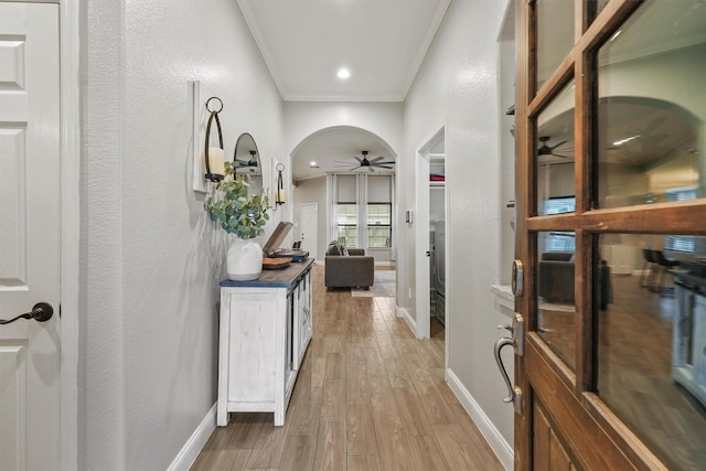 hall with crown molding, light wood-style flooring, and baseboards