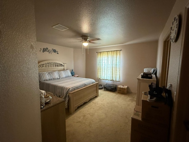 bedroom with a ceiling fan, light carpet, visible vents, and a textured ceiling