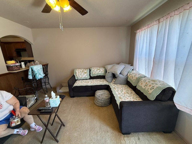 living room with ceiling fan, carpet flooring, and arched walkways