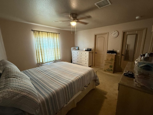 bedroom with a textured ceiling, ceiling fan, visible vents, and light colored carpet