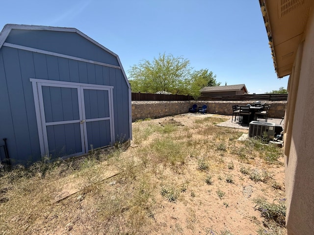 view of yard with central air condition unit, a storage shed, a patio, an outbuilding, and a fenced backyard