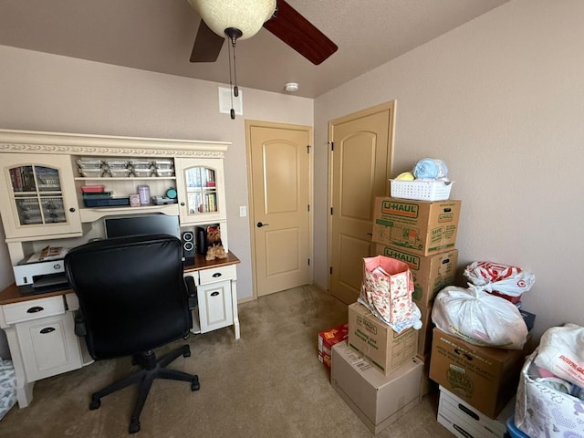 carpeted office with a ceiling fan