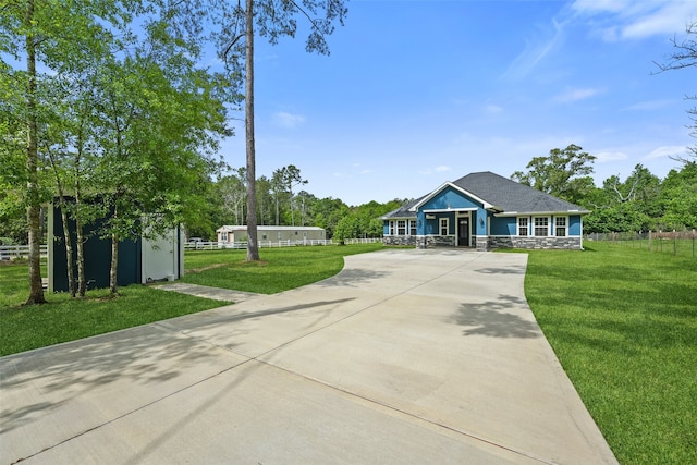 view of front of property featuring concrete driveway, fence, a front lawn, and stone siding