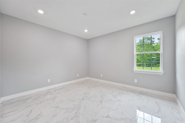empty room featuring marble finish floor, baseboards, and recessed lighting