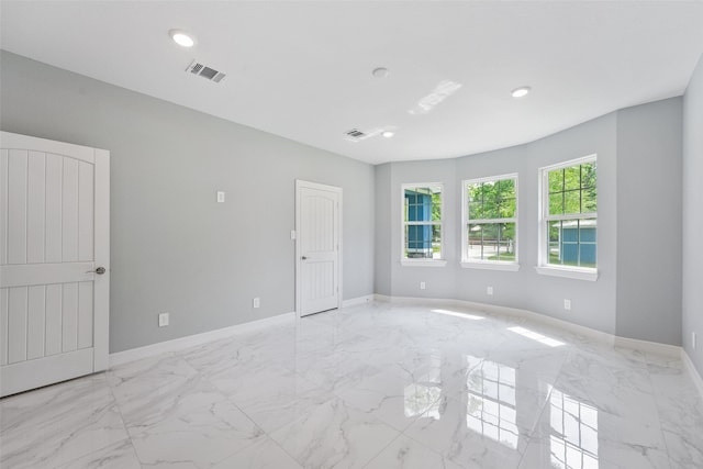 empty room featuring marble finish floor, baseboards, and visible vents
