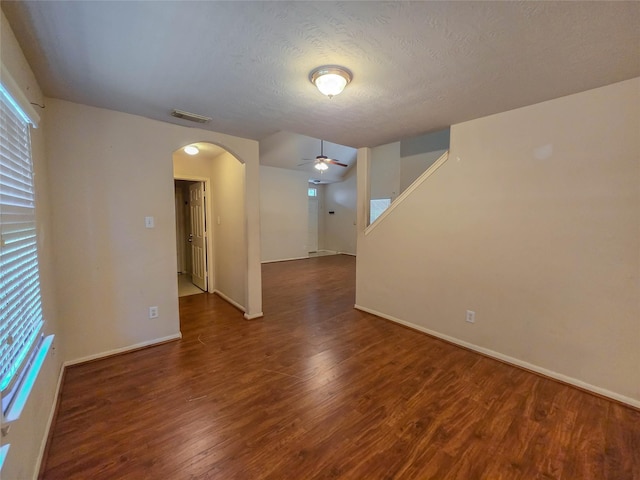 spare room with wood finished floors, visible vents, arched walkways, a ceiling fan, and baseboards