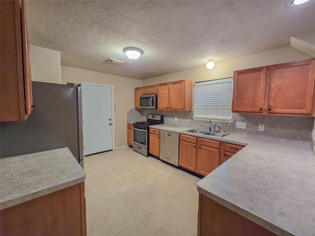 kitchen featuring brown cabinets, light floors, appliances with stainless steel finishes, and a sink
