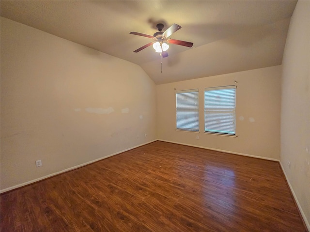 spare room featuring ceiling fan, lofted ceiling, baseboards, and dark wood-type flooring