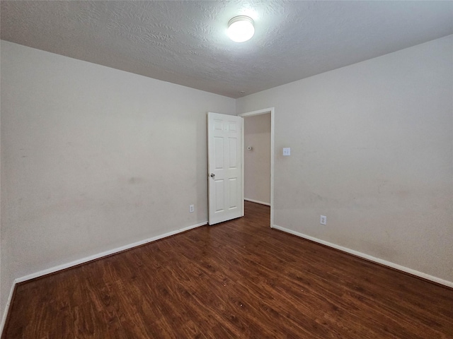 empty room with baseboards and dark wood-type flooring