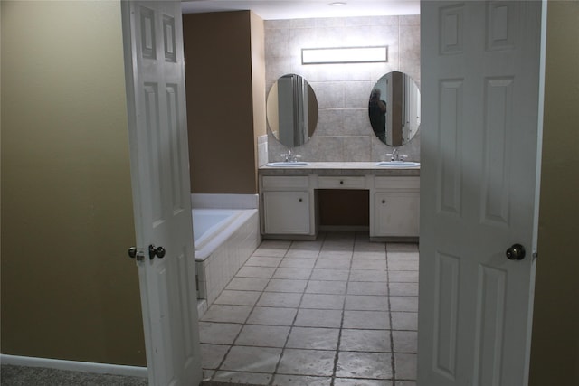 bathroom with a sink, double vanity, tiled tub, and tile patterned floors