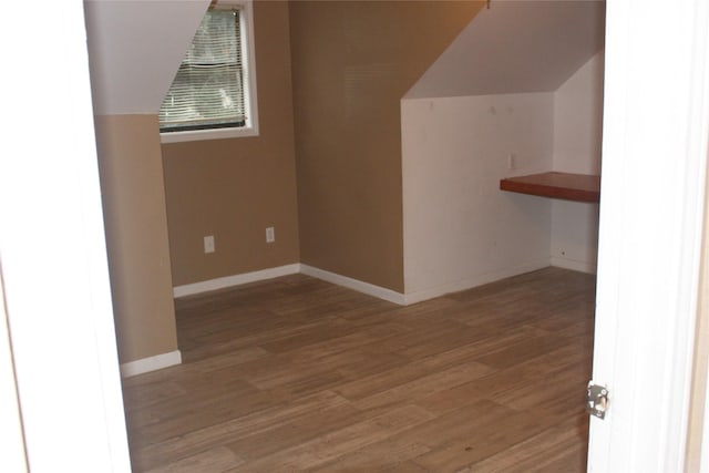additional living space with wood finished floors, vaulted ceiling, and baseboards