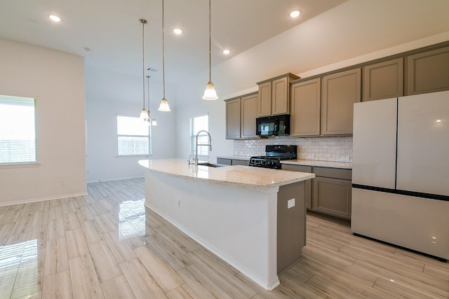 7634 Wrightwood Dr, Pasadena, TX 77505 - kitchen featuring hanging light fixtures, an island with sink, a sink, black appliances, and decorative backsplash