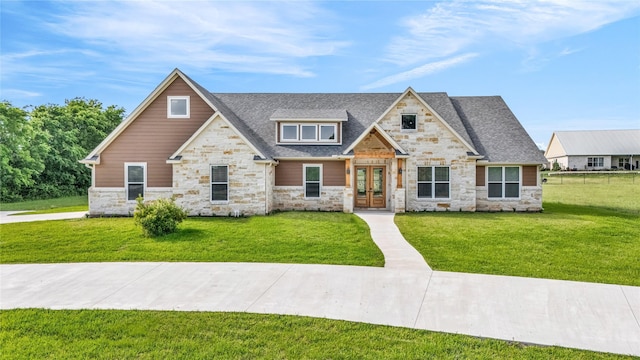 215 Carey Dr, Brenham, TX 77833 - craftsman house featuring stone siding, roof with shingles, french doors, and a front yard