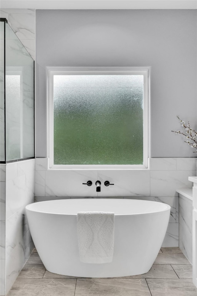 215 Carey Dr, Brenham, TX 77833 - full bathroom featuring tile walls, a wealth of natural light, and a freestanding bath