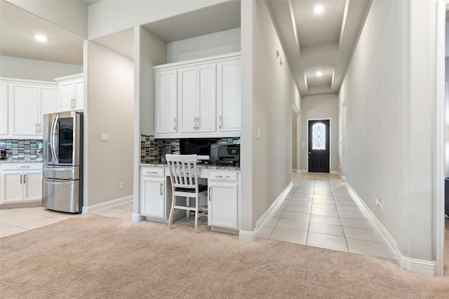 1806 Bridge Gate Ln, Katy, TX 77494 - interior space featuring light colored carpet, decorative backsplash, stainless steel fridge, light tile patterned floors, and white cabinets