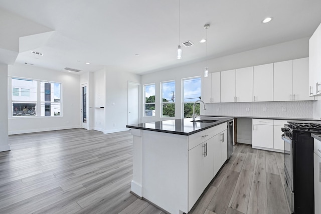 3313 Baer St, Houston, TX 77020 - kitchen featuring stainless steel appliances, a sink, dark countertops, light wood-style flooring, and open floor plan