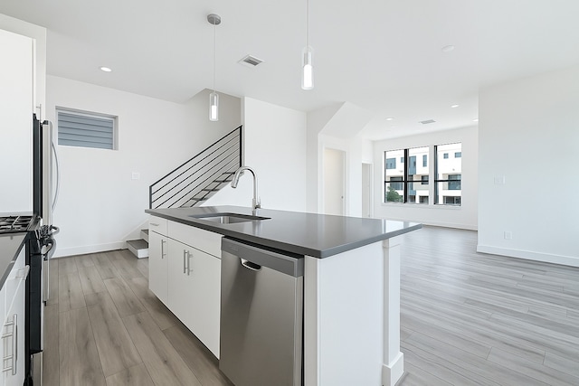 3313 Baer St, Houston, TX 77020 - kitchen featuring a sink, stainless steel appliances, dark countertops, light wood finished floors, and a center island with sink