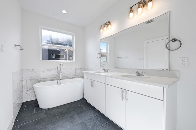 3313 Baer St, Houston, TX 77020 - full bath featuring tile walls, double vanity, a freestanding tub, a wainscoted wall, and recessed lighting
