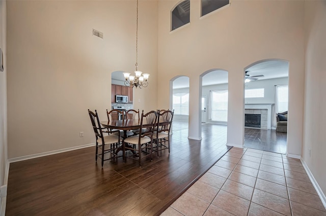 2107 Auburn Vale St, Katy, TX 77493 - dining area with visible vents, ceiling fan with notable chandelier, arched walkways, a fireplace, and a high ceiling
