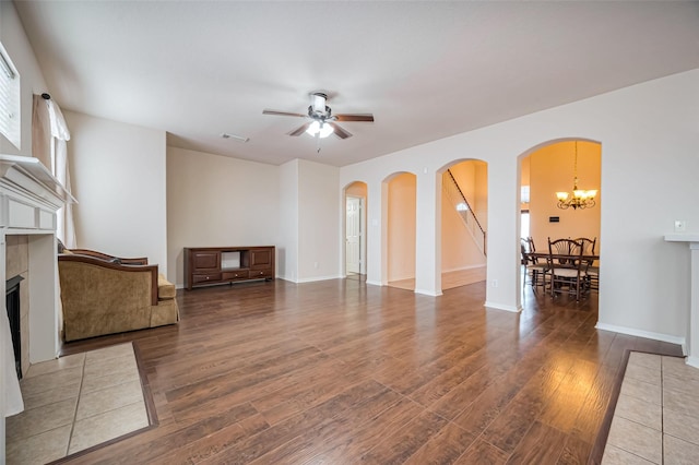 2107 Auburn Vale St, Katy, TX 77493 - unfurnished living room featuring ceiling fan with notable chandelier, wood finished floors, visible vents, arched walkways, and a tiled fireplace