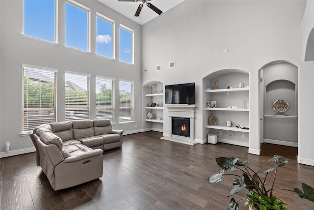 10610 Grace Hollow Dr, Cypress, TX 77433 - living room with built in shelves, a ceiling fan, a high ceiling, baseboards, and a glass covered fireplace
