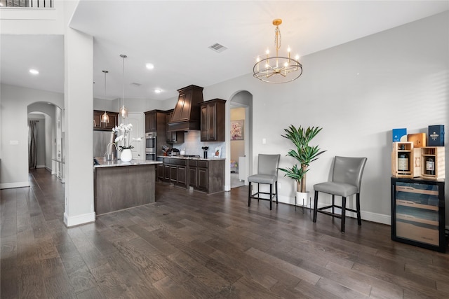 10610 Grace Hollow Dr, Cypress, TX 77433 - kitchen featuring a notable chandelier, dark brown cabinetry, arched walkways, and wine cooler