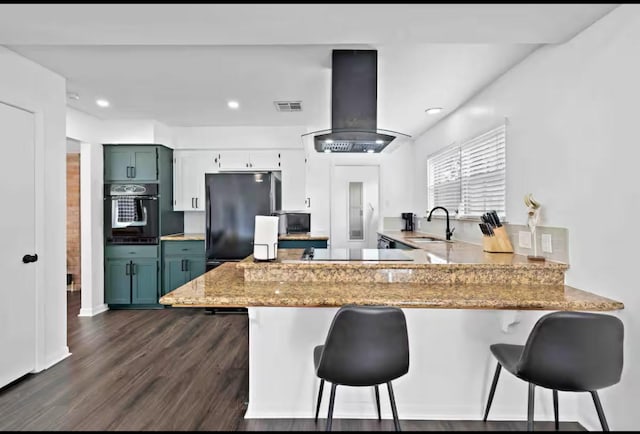 kitchen featuring a sink, a peninsula, exhaust hood, black appliances, and visible vents