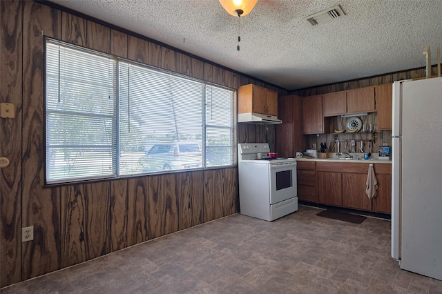 161281/2 Ridlon St, Channelview, TX 77530 - kitchen with white appliances, under cabinet range hood, light countertops, a textured ceiling, and wood walls