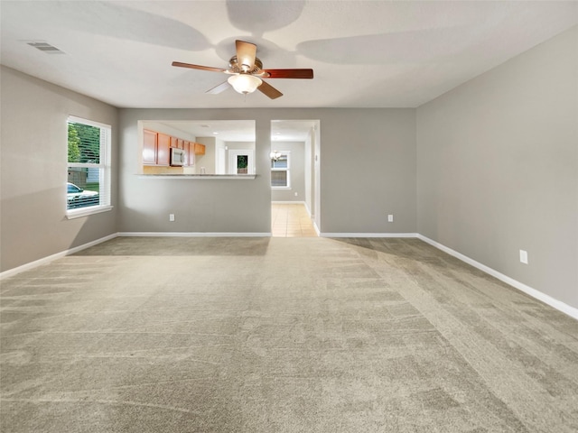unfurnished room featuring baseboards, light carpet, visible vents, and ceiling fan