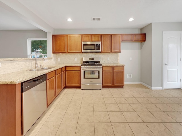 kitchen with a sink, stainless steel appliances, brown cabinetry, visible vents, and tasteful backsplash