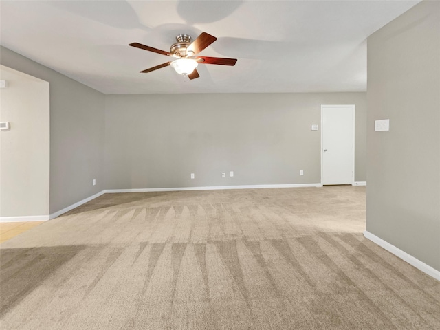 spare room with light colored carpet, baseboards, and ceiling fan