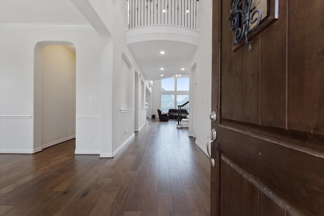 entrance foyer with arched walkways, baseboards, dark wood-type flooring, ornamental molding, and recessed lighting