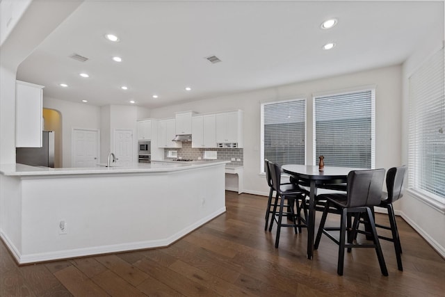 kitchen with stainless steel appliances, a sink, dark wood finished floors, recessed lighting, and white cabinets