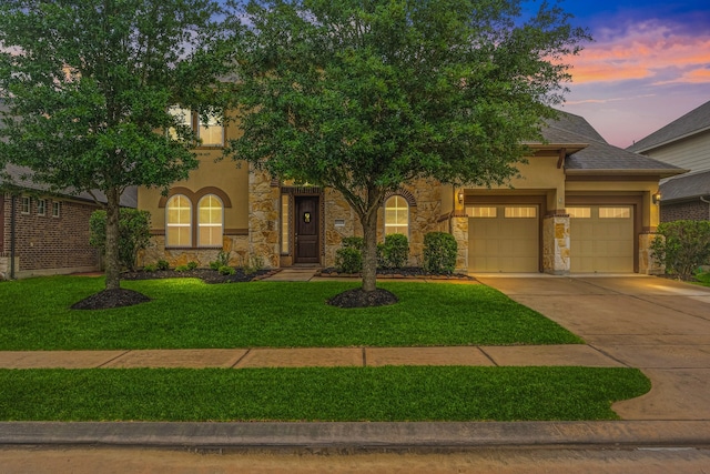 view of front facade with stucco siding, stone siding, a garage, driveway, and a yard