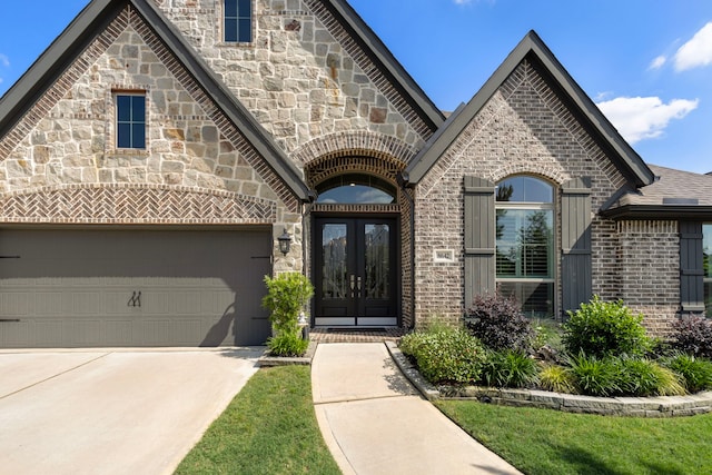 8642 Burdekin Rd, Magnolia, TX 77354 - view of exterior entry featuring french doors, brick siding, concrete driveway, and stone siding