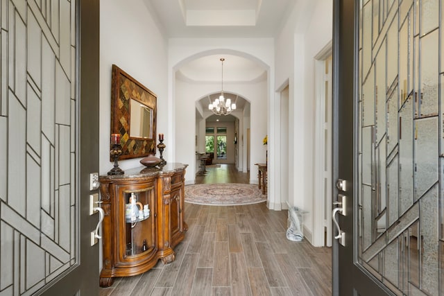 8642 Burdekin Rd, Magnolia, TX 77354 - entryway featuring arched walkways, a tray ceiling, dark wood-style flooring, and a chandelier
