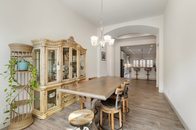 8642 Burdekin Rd, Magnolia, TX 77354 - dining room with arched walkways, a chandelier, light wood finished floors, and baseboards