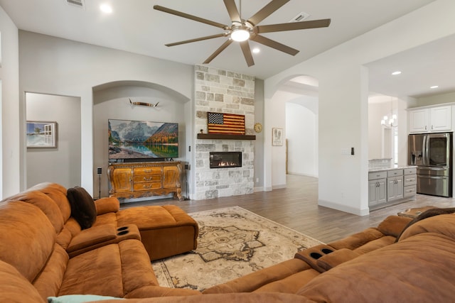 8642 Burdekin Rd, Magnolia, TX 77354 - living room featuring ceiling fan, light wood-style flooring, recessed lighting, arched walkways, and a fireplace