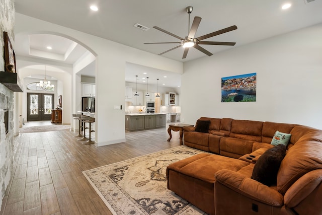 8642 Burdekin Rd, Magnolia, TX 77354 - living area featuring arched walkways, a ceiling fan, light wood-style flooring, a chandelier, and baseboards