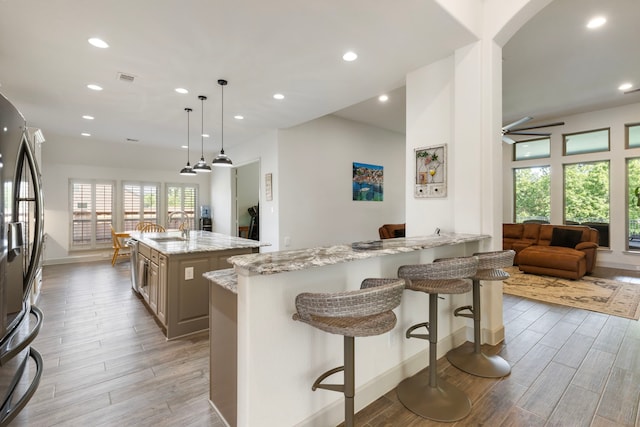 8642 Burdekin Rd, Magnolia, TX 77354 - kitchen with freestanding refrigerator, a sink, light wood-style floors, a kitchen breakfast bar, and recessed lighting