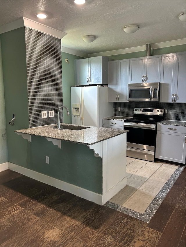301 Rd 5232, Cleveland, TX 77327 - kitchen featuring a breakfast bar, a sink, stainless steel appliances, light stone countertops, and backsplash