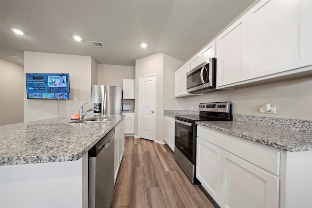 327 Pecos Dr, Huntsville, TX 77340 - kitchen featuring stainless steel appliances, a sink, wood finished floors, white cabinetry, and recessed lighting