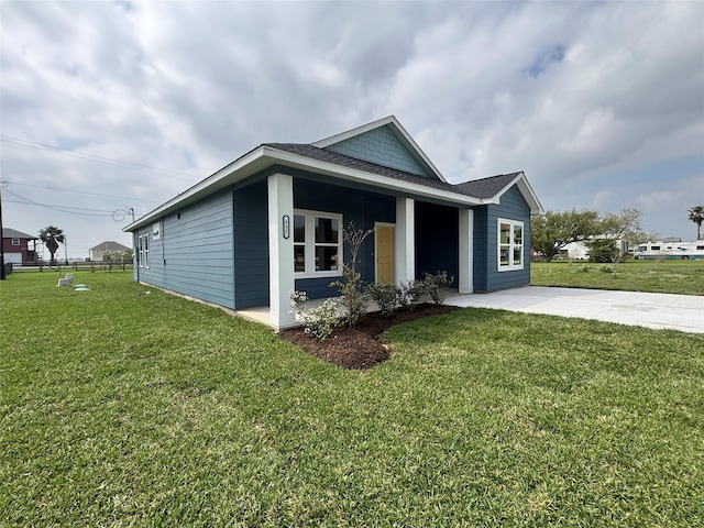 view of front of home with roof with shingles, fence, a front lawn, and concrete driveway