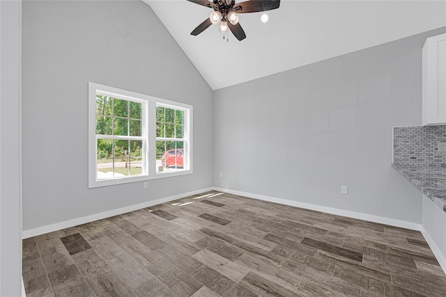unfurnished room featuring baseboards, ceiling fan, and high vaulted ceiling
