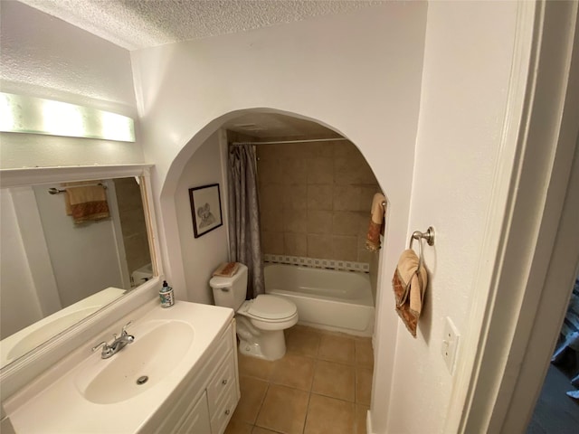bathroom featuring tile patterned floors, a textured ceiling, toilet, vanity, and shower / tub combo with curtain