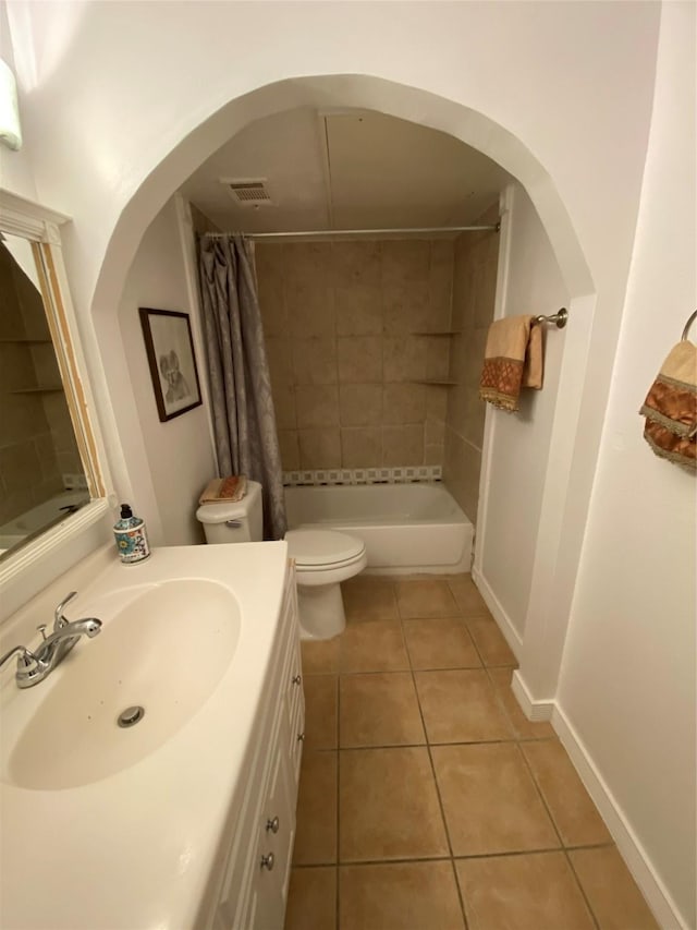 bathroom featuring tile patterned floors, toilet, vanity, shower / tub combo with curtain, and baseboards